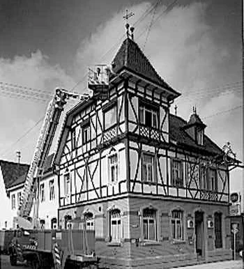 Historisches Schwarzweißfoto: Gebäude von außen, links ausgefahrene Arbeitsbühne