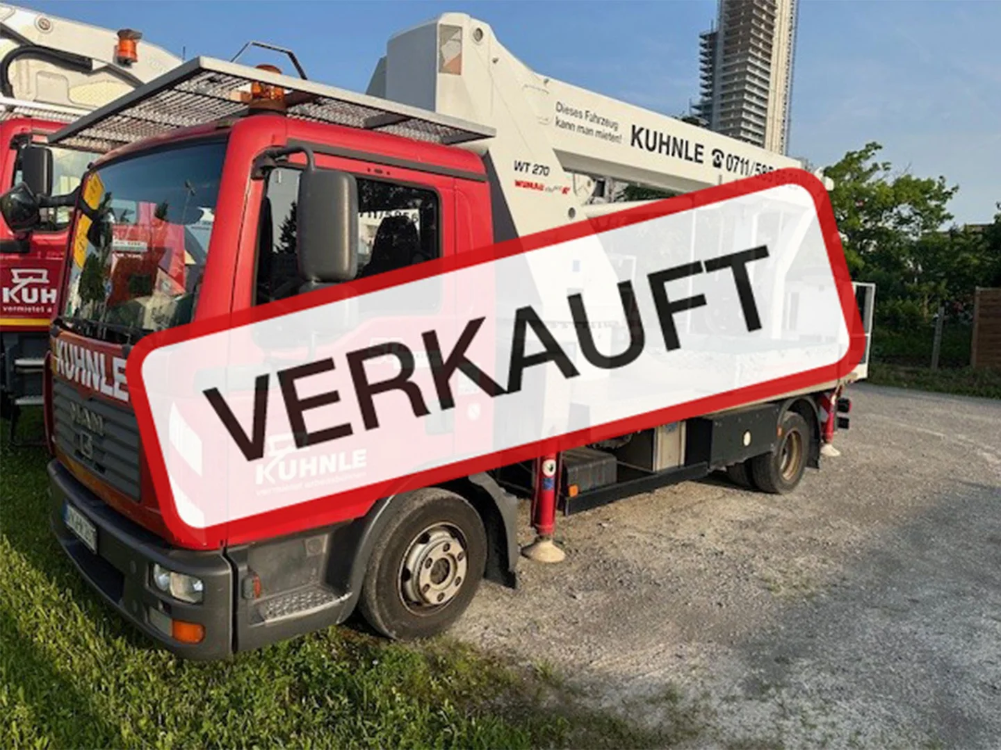 Arbeitsbühne teils auf Wiese und Straße geparkt, "Verkauft"-Text darüber.